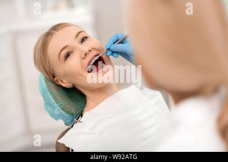 Contrôle de dentiste accolades de sa bonne humeur patient. Banque D'Images