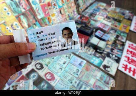 Un homme montre une fausse carte d'identité chinoise du président américain Barack Obama pour la vente à un décrochage dans une rue de la ville de Guangzhou, province de Guangdong, en Chine du sud Banque D'Images