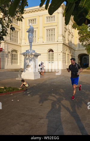 Un jogger passe devant la statue au Raffles' Raffles Landing Site par la rivière Singapour, Singapour, le Museum of asian civilisations dans l'arrière-plan Banque D'Images