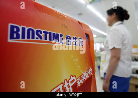 --FILE--un employé chinois passe devant une publicité de la société chinoise Biostime formule à un supermarché à Shanghai, Chine, le 10 juillet 2013. Des concurrents chinois Banque D'Images