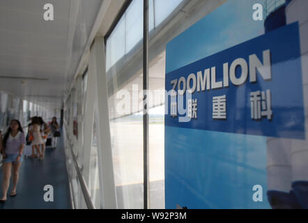 --FILE--passagers à pied passé une publicité de Zoomlion à l'Changsha Huanghua International Airport à Changsha, province du Hunan, Chine centrale 1 Banque D'Images