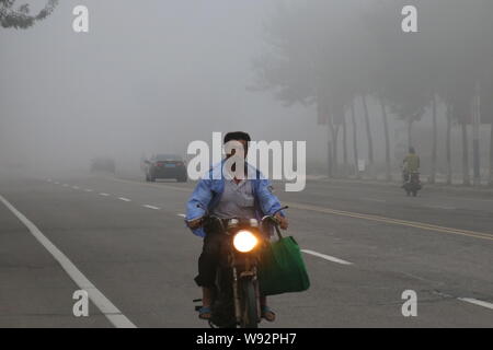 --FILE--un cycliste lourd dans le smog dans Shanghai, Chine de l'est la province de Shandong, le 31 juillet 2013. Le gouvernement central a mis son premier niveau provincial Banque D'Images