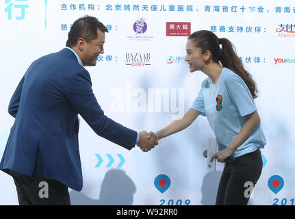 L'acteur chinois Li Yapeng, gauche, serre la main avec l'actrice de Hong Kong au cours d'un Angelababy événement promotionnel pour le sourire Angel Foundation à Beijing, Chi Banque D'Images