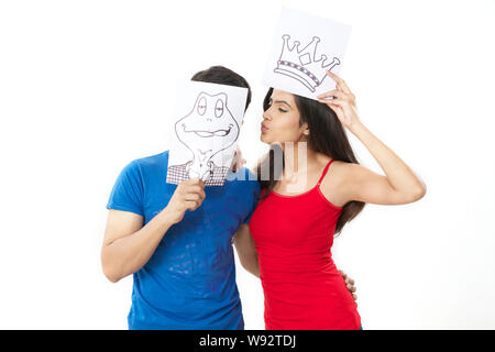 Young woman pretending to be a princess in a fairytale kissing a prince frog Stock Photo