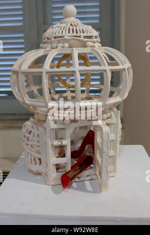 Le faux amour, représenté par la cage, qui emprisonne une femme maltraitée, représenté par les chaussures rouges Banque D'Images