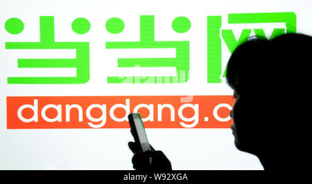 --FILE--une femme utilise son téléphone mobile devant une publicité de site d'achat en ligne dangdang.com à Shaoyang, Chine centrale Hunan provinc Banque D'Images