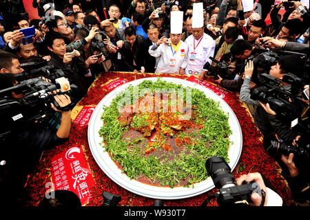 Les journalistes et les visiteurs de prendre des photos et vidéos d'un gigantesque plat de poisson cuit à la vapeur avec les dés de poivrons et les chefs au cours de la 23e Chef chinois Banque D'Images