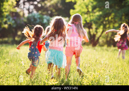 Grand groupe d'enfants, amis, garçons et filles courir dans le parc aux beaux jours d'été dans des vêtements décontractés . Banque D'Images