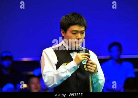 Ding Junhui de Chine les craies son cue qu'il estime une tourné contre John Higgins, de l'Angleterre lors d'un match de la finale 2013 Haikou World Open i Banque D'Images