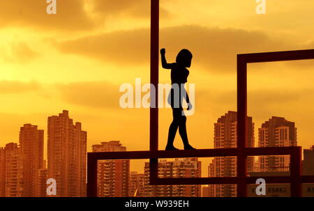 --FILE--une sculpture montrant une femme de garder l'équilibre sur une poutre est vu en face de tours d'immeubles d'habitation à Shanghai, Chine, 2 Marc Banque D'Images