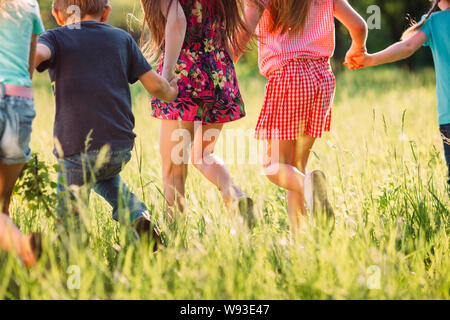 Grand groupe d'enfants, amis, garçons et filles courir dans le parc aux beaux jours d'été dans des vêtements décontractés . Banque D'Images