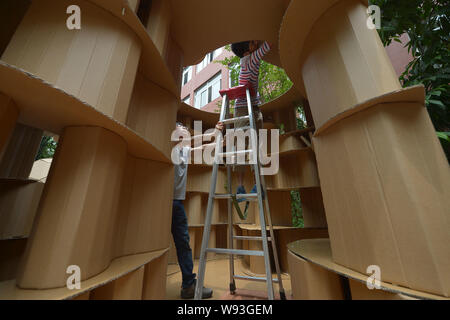 Un étudiant chinois met la touche finale sur une maison en carton à l'Université de Chongqing à Chongqing, Chine, 20 mai 2013. Plus de 200 étudiants f Banque D'Images