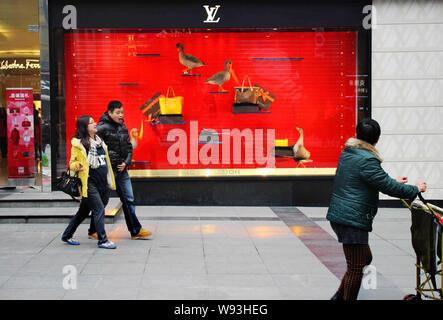 --FILE--piétons passent devant un magasin de la marque de luxe Louis Vuitton à Chongqing, Chine, 14 décembre 2013. Le marché du luxe seuls cordons ombilicaux vers chinois Banque D'Images