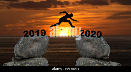 Un homme jump entre 2019 et 2020 ans d'un rocher à un autre rocher pendant le coucher du soleil Banque D'Images