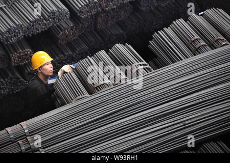 --FILE--Un travailleur chinois examine une pile de barres d'armature en acier à destination à une usine de transformation de l'acier, de l'est comté Ganyu Chines Jiangsu pr Banque D'Images