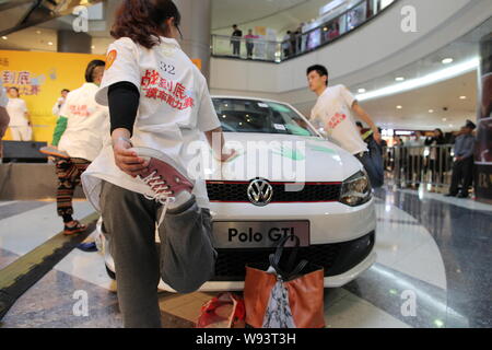 Les concurrents chinois se détendre leurs jambes comme ils garder leurs mains sur une Volkswagen Polo GTI pendant une main-sur-compétition d'endurance voiture de Super Brand Mall Banque D'Images