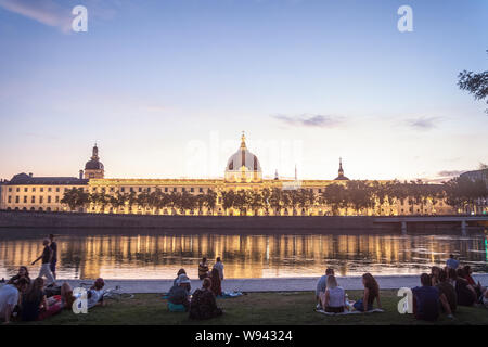 LYON, FRANCE - Le 18 juillet 2019:l'anglais des gens assis sur la rive de la quais de Rhône, en face de l'Hôtel-Dieu, l'un des principaux monuments de la ville fo Banque D'Images