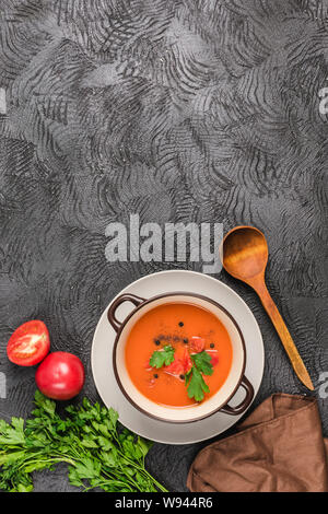 Soupe froide espagnole gaspacho de tomates, poivre, ail et fines herbes dans une plaque sombre sur fond noir Vue supérieure avec copyspace. La nourriture végétarienne Banque D'Images