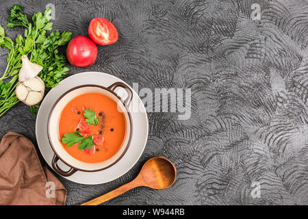 Soupe froide espagnole gaspacho de tomates, poivre, ail et fines herbes dans une plaque sombre sur fond noir Vue supérieure avec copyspace. La nourriture végétarienne Banque D'Images