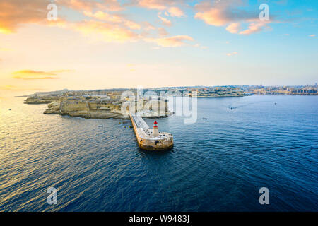 Lever du soleil sur l'Ricasoli Point Lighthouse au port de La Valette sur l'île méditerranéenne de Malte par un chaud matin d'été Banque D'Images