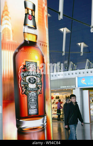 --FILE--passagers à pied passé une publicité pour le Whisky Chivas à l'Aéroport International de Shanghai Pudong à Shanghai, Chine, le 8 avril 2011. Pern Banque D'Images