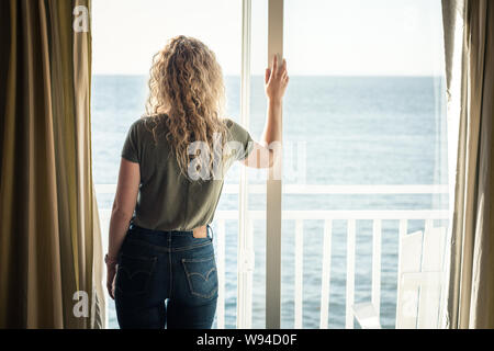 Femme blonde à la recherche à la vue par la fenêtre Banque D'Images