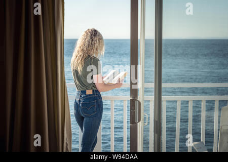 Blonde femme lisant un livre en face de la mer Banque D'Images