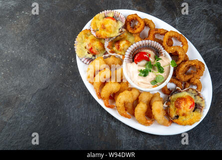 La nourriture péruvienne. Piqueo caliente. Fun pour plateau de fruits de mer crevettes frites, calamars cuits et anneaux de pétoncles avec sauce. Banque D'Images