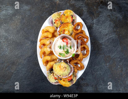 La nourriture péruvienne. Piqueo caliente. Fun pour plateau de fruits de mer crevettes frites, calamars cuits et anneaux de pétoncles avec sauce. Banque D'Images