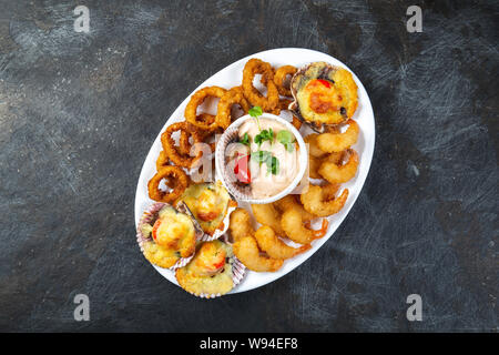 La nourriture péruvienne. Piqueo caliente. Fun pour plateau de fruits de mer crevettes frites, calamars cuits et anneaux de pétoncles avec sauce. Banque D'Images