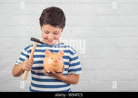 Enfant drôle avec tirelire contre fond brique Banque D'Images