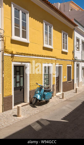 Maison Jaune avec Moto Scooter bleu stationné à l'extérieur dans la ville de Lagos dans l'Algarve Portugal Banque D'Images