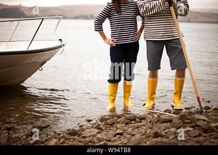 Up d'un couple portant des bottes sur un rivage rocailleux Banque D'Images