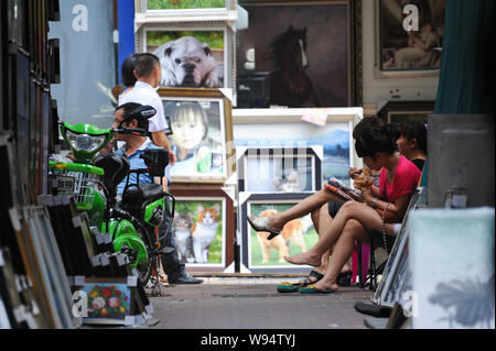 Passer le temps des vendeurs à l'extérieur de leurs magasins à Dafen, Shenzhen, Chine du sud, la province du Guangdong, le 19 septembre 2012. Da Banque D'Images