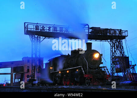 Une locomotive à vapeur passe sous une grue dans la ville de Chifeng, Chine du nord Région autonome de Mongolie intérieure, le 5 janvier 2012. Chines rail system est l'un en Banque D'Images