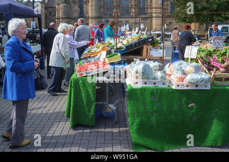 Marché de rue avec des personnes âgées à shoppers un marché de fruits et légumes sur la place du marché de décrochage, Hexham, Northumberland Banque D'Images