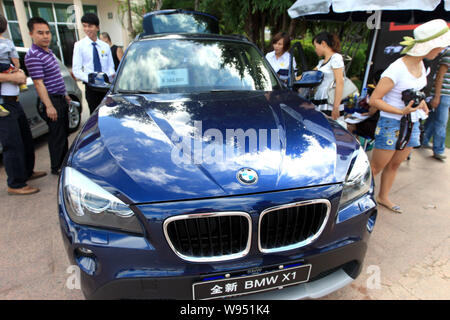 --FILE--visiteurs regarder une BMW X1 au cours d'une auto show de la ville de Sanya, province de Hainan, Chine du Sud, du 17 novembre 2011. Voiture de luxe allemande BMW et bouilloire Banque D'Images