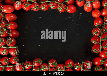 Groupe de tomates cerises sur du marbre noir comme conseil, organisé dans le cadre autour, l'espace rectangulaire de texte dans un milieu Banque D'Images