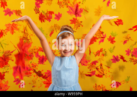 Petite fille dans un costume de princesse sur un contexte de baisse les feuilles d'automne. Heureux l'enfant leva les mains vers le haut. Concept pour l'automne, maison de vacances, halloween, s Banque D'Images