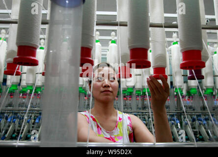 --FILE--une femme travailleur chinois s'occupe de la production de fils à destination de l'Asie du Sud-Est sur une machine à filer dans une usine de textile à Huaibei Banque D'Images