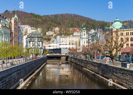 Vue au-dessus de la rivière Teplá, avec promenade et sur la rue Riverside avec arrière-plan de Hot Spring Colonnade, Église de Saint Madeleine et hill. Banque D'Images