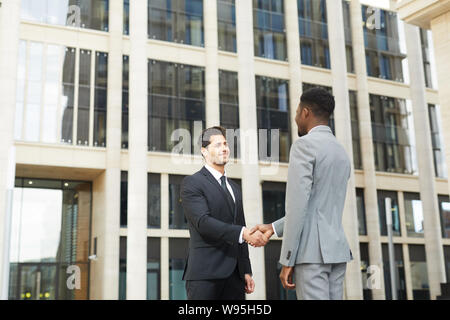 Deux jeunes businessmen standing smiling et chaque message d'autres près de l'immeuble de bureaux à l'extérieur Banque D'Images