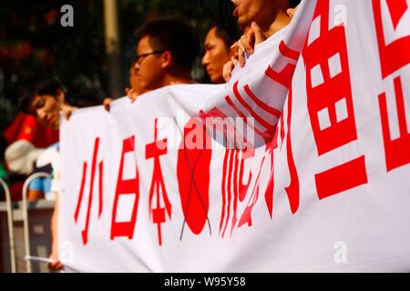 Des manifestants chinois tenir le haut d'une bannière avec des pancartes, Little Japanese ramper hors de l'île Diaoyu, lors d'une manifestation devant l'ambassade du Japon o Banque D'Images