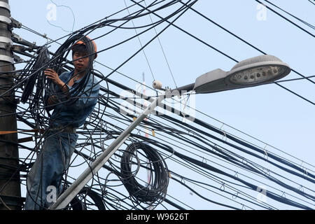 Un électricien chinois vérifie et répare des fils électriques sur un poteau à Shanghai, Chine, le 7 mai 2012. La Chine peut voir la croissance de son électricité cons Banque D'Images