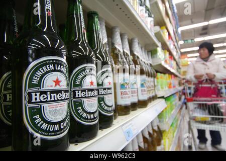 --File--un client shop pour les boissons à côté de bouteilles de bière Heineken dans un supermarché à Nantong, province du Jiangsu, Chine de l'est 8 avril 2011. Comme b Banque D'Images