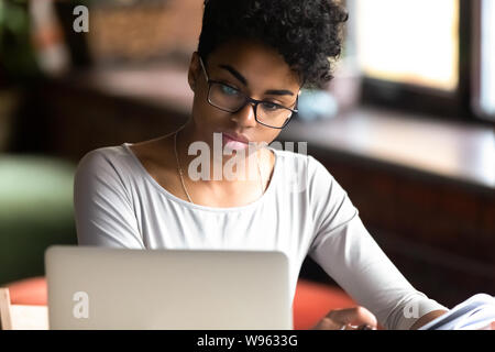 Thoughtful girl à biracial axé l'étude sur ordinateur portable lunettes Banque D'Images