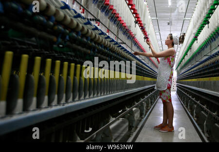 --FILE--une femme travailleur chinois s'occupe de la production de fils à destination de l'Asie du Sud-Est sur une machine à filer dans une usine de textile à Huaibei Banque D'Images