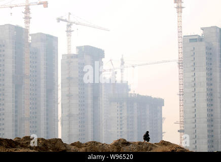 --FILE--un garde de sécurité chinois ressemble au nouveau appartement résidentiel Bâtiments en construction à Pékin, Chine, 27 décembre 2011. Prix des nouveaux Banque D'Images