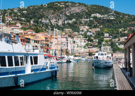 Villefranche, France, 2019-08-03. Offres boatmoored passager de quayside iwith émaille maisons du côté de colline derrière, à Villefranche sur le Sud o Banque D'Images