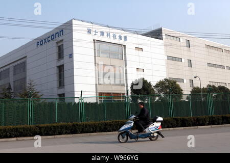 --File--Un homme chevauche son vélo électrique passé une usine de Foxconn dans la Zone Industrielle de Songjiang à Shanghai, Chine, 21 février 2011. Foxconn, l'o Banque D'Images